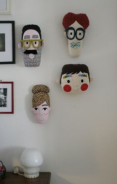 three masks are hanging on the wall above a table with a lamp and other items