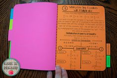 a hand holding an orange and pink notebook