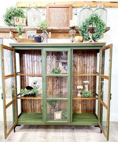 an old china cabinet is painted green and decorated with greenery