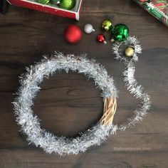 a christmas wreath with tinsel and ornaments around it on a wooden table next to other holiday decorations