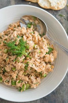 a white bowl filled with tuna salad next to crackers