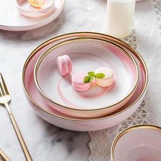 a pink and gold plate with two small pieces of candy in it on a white table cloth