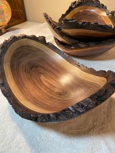 two wooden bowls sitting on top of a bed