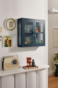 a blue cabinet sitting on top of a white table next to a wall mounted clock