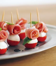 small appetizers are arranged on a plate with toothpicks in the shape of roses