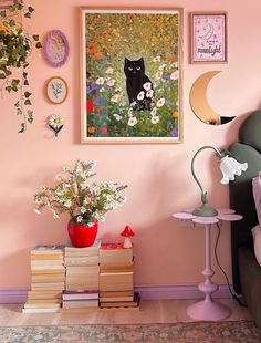 a bedroom with pink walls and pictures on the wall, flowers in vases and books