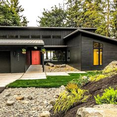 a black house with red door and green grass