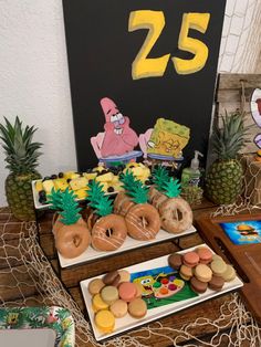 a table topped with donuts and pineapples next to a sign that says 25