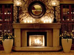 a fire place with candles and flowers in front of a stone fireplace surround by two large planters