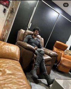 a man is sitting on a brown chair in a room with lots of leather furniture