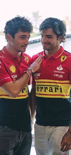 two men standing next to each other wearing red and yellow shirts