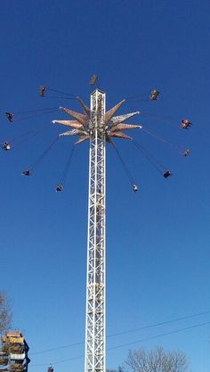 a ferris wheel with people riding it in the sky above some buildings and trees on a sunny day