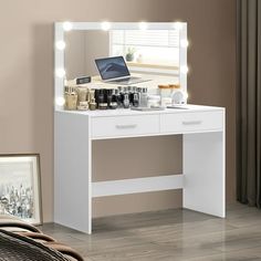 a white vanity with lights on it and a laptop sitting on top of the desk