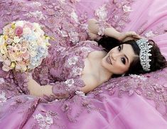 a woman in a pink dress laying on her stomach with a bouquet of flowers around her neck