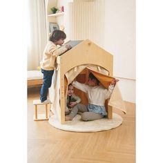 two children are playing in a wooden doll house