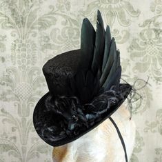 This elegant gothic mini top hat is covered with wonderful black brocade. It is luxuriously decorated with a unique hand-crafted faux raven wing along with curled ostrich spray and black blossoms with crystal details. IMPORTANT NOTE: The fabric seen in the pictures is permanently SOLD OUT! The hat you'll receive will be covered in the brocade seen in the LAST PICTURE. Measurements : height 4 inches( 10 cm ) front to back 9 inches ( 22 cm ) side to side 7.5 inches ( 19 cm ) This mini top hat is f Raven Wings, Steampunk Top Hat, Victorian Hats, Steampunk Hat, Mini Top Hat, Elegant Gothic, Mini Top, Diy Hat, Hat Ideas