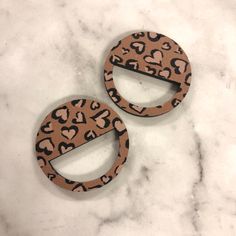 two leopard print wooden earrings on a marble surface