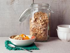 a glass jar filled with granola next to two bowls