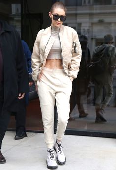 a woman in white pants and jacket walking down the street