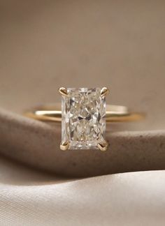 an engagement ring with a princess cut diamond in the center on top of a white cloth