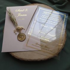 two wedding cards and a medal are on a wooden slice with green fabric in the background