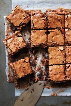 brownies cut into squares on top of parchment paper with a spatula next to them