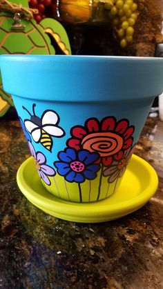 a blue flower pot sitting on top of a counter next to a yellow saucer