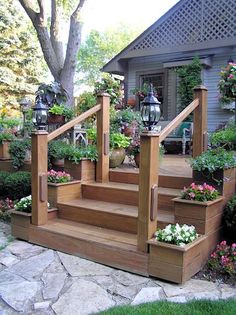 a set of wooden steps leading up to a house with potted plants on each step