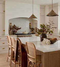 a kitchen with white cabinets and an island in the middle is surrounded by wooden chairs