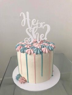 a white cake with blue and pink frosting on top that says, he or she