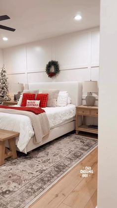 a bedroom decorated for christmas with white bedding and red pillows