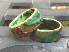 two green and brown rings sitting on top of a cement block wall next to each other