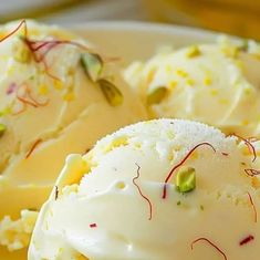 three desserts with white frosting and sprinkles are on a plate