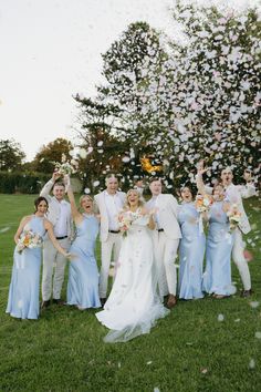 a group of people standing on top of a lush green field next to a tree