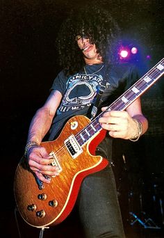 a man with long hair playing an electric guitar