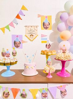 a table topped with cakes and cupcakes covered in frosting next to balloons