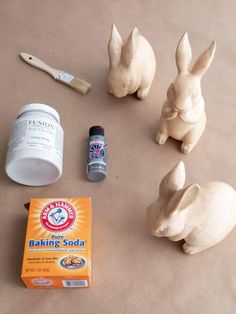 some bunny figurines are sitting on the floor next to baking soda bottles and a toothbrush