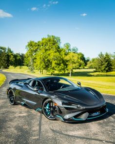 a black sports car parked on the side of a road in front of some trees