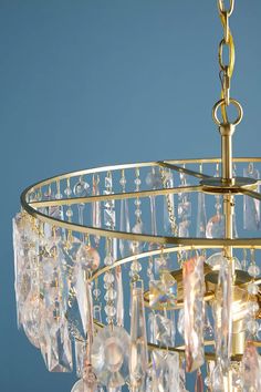 a gold chandelier with crystal drops hanging from it's center circle, against a blue background