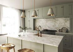 a kitchen with marble counter tops and two pendant lights hanging over the island in front of it