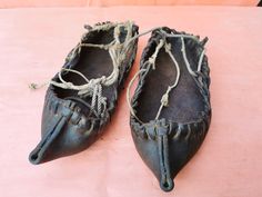 an old pair of shoes with rope on the soles sitting on a pink surface