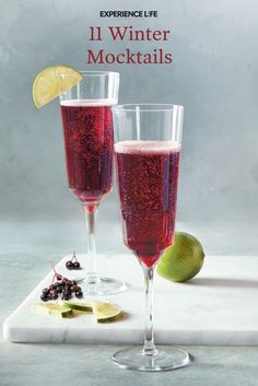 two wine glasses filled with liquid and garnished with limes