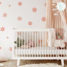 a baby's room with pink flowers on the wall and white crib bedding