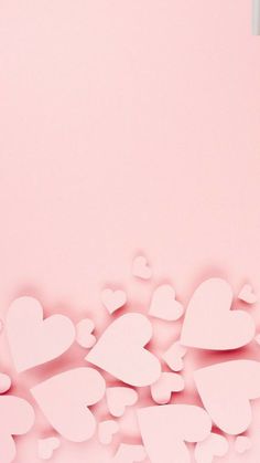 paper hearts are scattered on a pink background