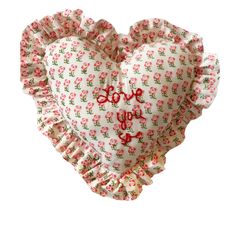 a heart shaped pillow with red flowers on the front and bottom, sitting in front of a white background