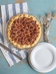 a table topped with a pie and silverware next to a plate on top of a striped napkin