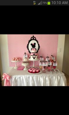 a table topped with lots of cupcakes next to a pink and white wall