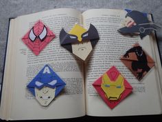 an open book with paper cut out of superheros and iron man faces on it