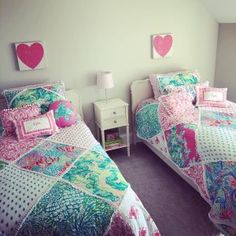 two beds in a room with pink and blue comforters on them, one has a heart shaped pillow