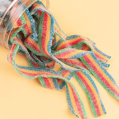 a jar filled with colorful striped ribbon on top of a yellow tablecloth covered floor